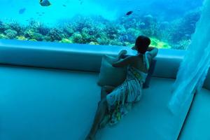 a person sitting on a ledge looking out at the water at Huvafen Fushi in North Male Atoll