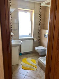 een badkamer met een wastafel, een toilet en een raam bij Zakątek in Porąbka