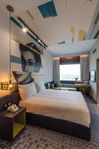 ドバイにあるStudio One Hotelの大きなベッドが備わる客室で、壁に絵画が飾られています。