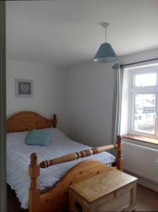 a bedroom with a wooden bed and a window at Sammy's place in Hayle