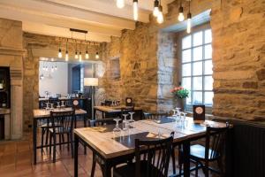Pluduno的住宿－La Pénate，一间设有桌椅的餐厅,位于带石墙的房间内