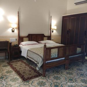 ein Schlafzimmer mit einem großen Bett mit einem Holzrahmen in der Unterkunft Hotel Jai Niwas in Jaipur