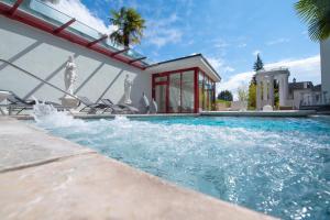 a swimming pool with chairs and a house at Hotel Rössli Gourmet & Spa in Weggis