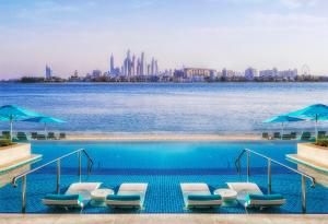 a row of lounge chairs sitting on top of a lake at The Retreat Palm Dubai MGallery by Sofitel in Dubai