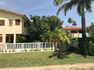 une maison avec une clôture blanche et des palmiers dans l'établissement Chalés Recanto dos Golfinhos, à Ponta do Funil