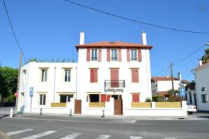 ein weißes Gebäude mit roten Rollläden auf einer Straße in der Unterkunft Duplex Elegant & Moderne - 3 chambres - Rooftop terrasse & Jacuzzi- Chélitz in Biarritz