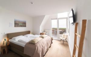 a white bedroom with a bed and a window at Het Vlielandhotel in Oost-Vlieland