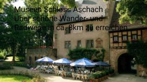 a restaurant with tables and umbrellas in front of a building at Ferienwohnung Sandner in Nüdlingen