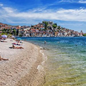 a beach with people laying on the sand and the water at Ivana Šibenik in Šibenik