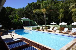 a swimming pool with lounge chairs and a table next to it at Pousada Aguas Claras in Búzios