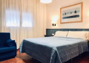 a bedroom with a bed and a blue chair at Hostal Playa in Punta Umbría