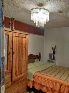 1 dormitorio con cama y lámpara de araña en Escocie - Vargas, en Quito