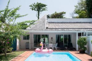 a swimming pool with a pink inflatable flamingos in front of a house at Baan Promphun Pool Villa by BV in Ban Pa Khlok