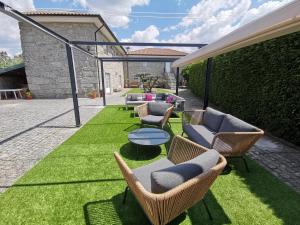 a patio with chairs and a table on grass at Villa Moura - Pool & Jacuzzi in Póvoa de Lanhoso