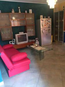 a living room with a red couch and a refrigerator at la casa di laura in Calascibetta