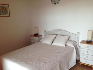 een slaapkamer met een wit bed met 2 nachtkastjes en een dressoir bij Casa Victor in Playa Migjorn
