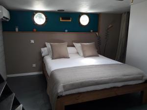 a large bed in a small room with two windows at Péniche La Belle Aimée in Aigues-Mortes
