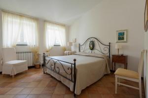 sypialnia z łóżkiem, krzesłem i oknami w obiekcie Agriturismo Villa Caterina w mieście Levanto