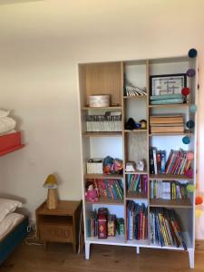 ein Bücherregal mit Büchern neben einem Bett in der Unterkunft Maison familiale au calme/5 chambres/Grand jardin in Bangor