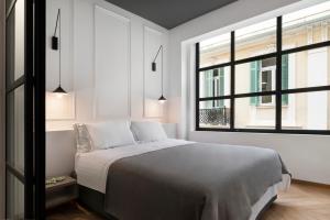 a white bedroom with a bed and two windows at La Maison Athenes in Athens