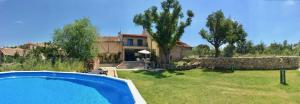 a house with a swimming pool in front of a yard at Casa los Tres Nogales in Castroserna de Arriba