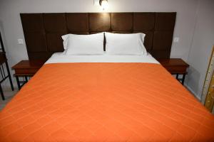 a bed with an orange comforter and two tables at Seaview in Agios Georgios