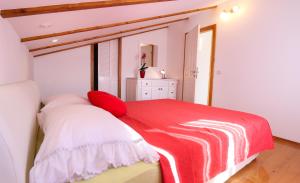 a bedroom with a red and white bed with a window at Apartmani Pavla in Orebić