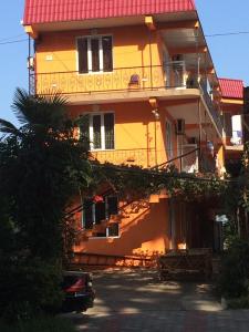 a yellow building with a balcony and a car parked in front at Hotel Kobuleti in K'obulet'i