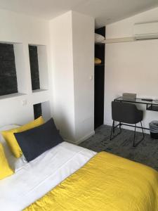 a bedroom with a yellow and white bed and a desk at Hôtel Le Mistral in Marseille