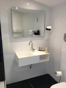 a white bathroom with a sink and a mirror at Hôtel Le Mistral in Marseille