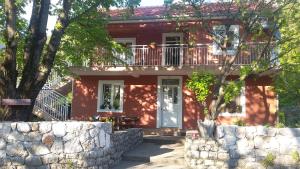 une maison rouge avec un balcon et une clôture dans l'établissement Apartman Vesna, à Virpazar