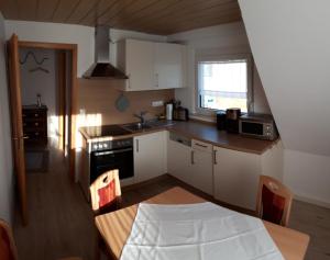 a kitchen with white cabinets and a table and a window at Weinbergblick in Ramsthal