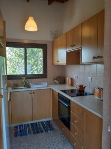 a small kitchen with wooden cabinets and a window at ARODAFNI HOUSE. Unique views and amazing sunsets. in Kouklia