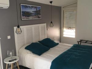a bedroom with a white bed with blue pillows at Hôtel Le Mistral in Marseille
