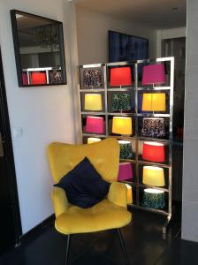a yellow chair in front of a shelf with colorful objects at Hôtel Le Mistral in Marseille