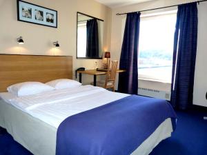 a bedroom with a large bed and a desk and a window at Hotel Riverside in Uddevalla