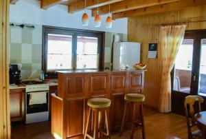 a kitchen with wooden cabinets and stools in a room at Ivola Vendégház in Izvoare