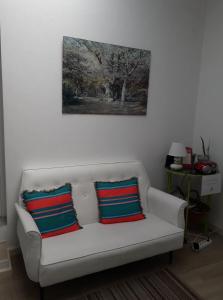 Un sofá blanco con dos almohadas coloridas. en Pés Verdes-Alojamento e Chá en Ponta Delgada