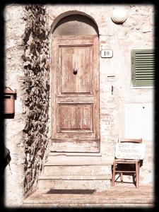 eine Holztür an der Seite eines Gebäudes mit einem Stuhl in der Unterkunft La casa di Pasquino in Lama