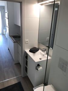 ein weißes Badezimmer mit einem Waschbecken und einem Spiegel in der Unterkunft Zeebriesje in Oostduinkerke
