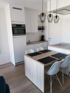 a kitchen with white cabinets and a kitchen island with chairs at Zeebriesje in Oostduinkerke