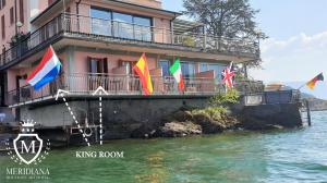 a building with flags on the side of the water at Hotel Meridiana in Bellano