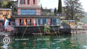 une maison sur l'eau avec des drapeaux devant elle dans l'établissement Hotel Meridiana, à Bellano