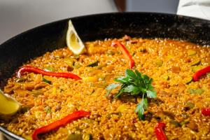 a bowl of rice with peppers and a garnishment at Hotel Boutique Calas de Alicante in Alicante