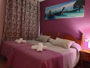 two beds in a bedroom with pink walls at Pension los Verdiales in La Herradura