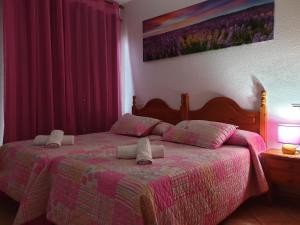 a bedroom with a bed with a pink comforter at Pension los Verdiales in La Herradura