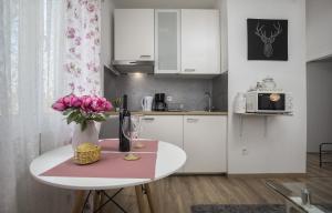 a kitchen with a table with a vase of pink flowers at Apartman Anastazija in Rovinj