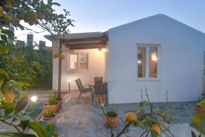 a white house with a patio with a table and chairs at The Olive Garden House in Haraki