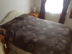 a bed with a brown blanket on top of it at 313 Sundowner Holiday Park Hemsby in Hemsby