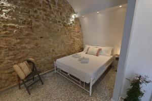 a bedroom with a bed and a stone wall at Yiasemi Corfu Luxury Studio in Corfu Town